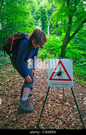 Europäische Rizinuspflanze Tick, europäischen Schafe Zecke (Ixodes Ricinus), Frau in Panik gerade einen Tick-Warnschild Stockfoto