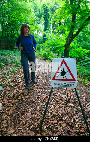 Europäische Rizinuspflanze Tick, europäischen Schafe Zecke (Ixodes Ricinus), Frau mit einem Tick-Warnschild Stockfoto