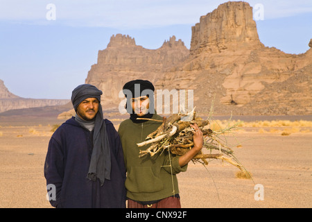 zwei junge Ouaregs sammeln von Brennholz vor dem Panorama der Tadrart Acacus, Libyen, Sahara Stockfoto