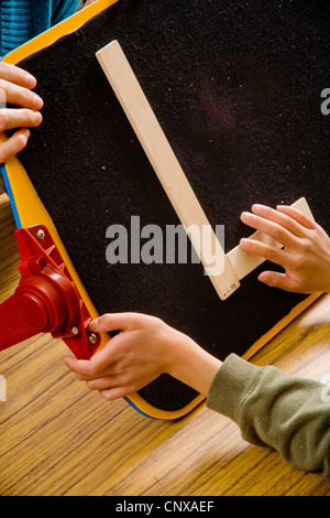 Ein Lehrer führt ein blindes Kind Hände, um den Buchstaben "L" bilden durch Berührung mit zwei Stöcken in einem speziellen Pre-Braille Schrift c braucht Stockfoto