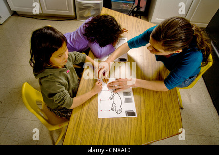 Ein Lehrer führt ein blindes Kind Hände über den Umriss einer Eidechse in erhöhten Art in einem besonderen Bedürfnissen, die Klasse zu schreiben. Stockfoto