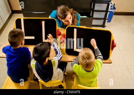 Ein Lehrer beobachtet, wie blinde jungen den Buchstaben "L bilden" durch Berührung mit zwei Stöcken eine in einem speziellen Pre-Braille schreiben Klasse braucht. Stockfoto