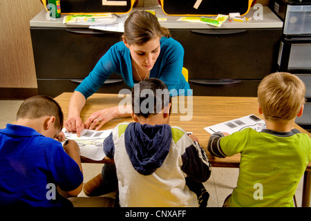 Eine Lehrer hilft Sehbehinderte jungen Farbe, die eine Eidechse mit Art ausgelöst, wenn sie durch Berührung in einem speziellen erkennen, benötigt Klasse. Stockfoto