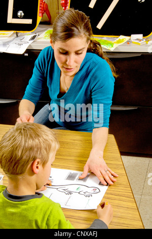 Eine Lehrer hilft Sehbehinderte junge Farbe, die eine Eidechse mit Art ausgelöst, wenn sie durch Berührung in einem speziellen erkennen, benötigt Klasse. Stockfoto