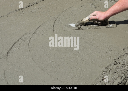 Eine Maurer Hand beendet einen neu gegossenen Betonboden Stockfoto