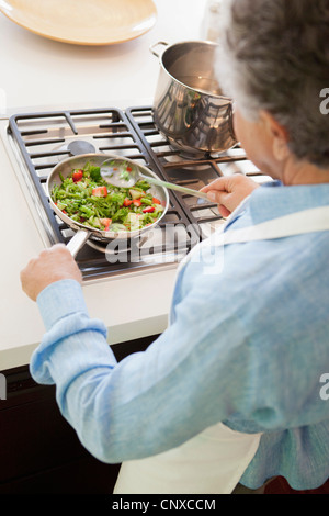 Über die Schulter-Blick von einem älteren Mann Kochen Gemüse Stockfoto