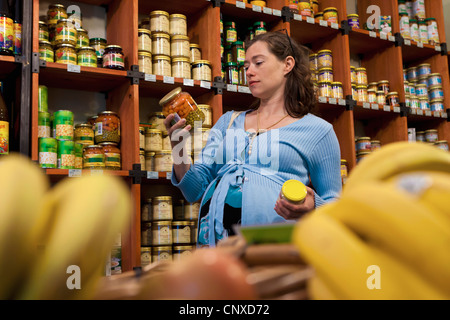 Eine schwangere Frau, wenn man bedenkt ein Glas mit Gemüse im Supermarkt Stockfoto