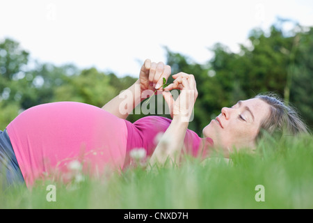 Eine schwangere Frau liegen in der Wiese, Seitenansicht Stockfoto