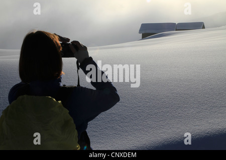 Wanderer findet Foto von verschneiten Blockhütten in der Ferne Stockfoto