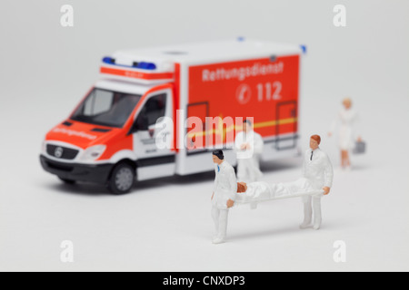 Miniatur-Sanitäter Figuren tragen eines Patienten auf einer Bahre von einem Spielzeug-Ambulanz Stockfoto