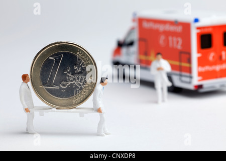 Miniatur Sanitäter Figuren tragen eine Euro-Münze auf einer Bahre in ein Spielzeug-Krankenwagen Stockfoto