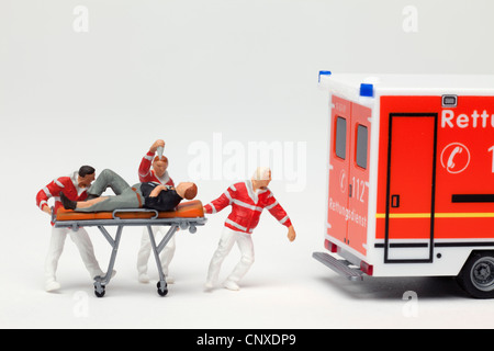 Miniatur-EMT-Figuren Machenschaften eines Patienten auf eine Bahre, eine Spielzeug-Ambulanz Stockfoto