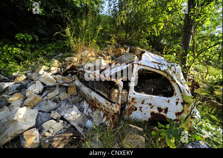 rostiges Autowrack und Felsbrocken, Italien, Ligurien Stockfoto