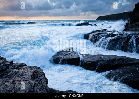 Surfen Sie über Felsen bei Flut an der kornischen Küste Trebarwith Strand brechen Stockfoto