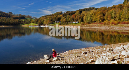 Frau am Seeufer von Henne Stausee sitzen und genießen Sie eine gute Aussicht, Meschede, Sauerland, Nordrhein-Westfalen, Deutschland Stockfoto