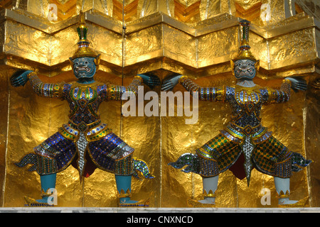 Yaksha Dämon Statuen bewachen die goldenen Chedi im Wat Phra Kaeo in Bangkok, Thailand. Stockfoto