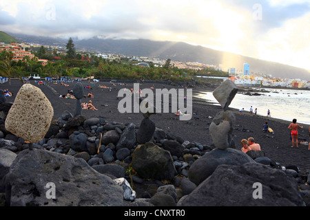 Stapel von Steinen und schwarzen Lavasand am Playa Jardin, Punta Brava im Hintergrund, Kanaren, Teneriffa, Puerto De La Cruz Stockfoto
