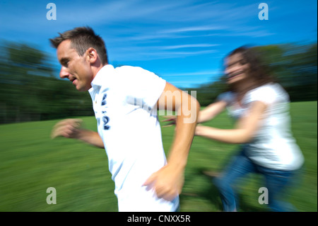 junges Paar läuft über eine Wiese herumalbern glücklich, Deutschland Stockfoto