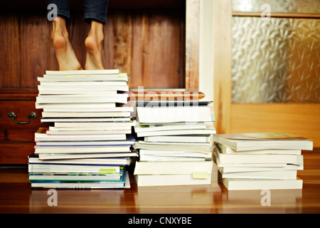 Mädchen steht Zehenspitzen auf Stapel Bücher Stockfoto