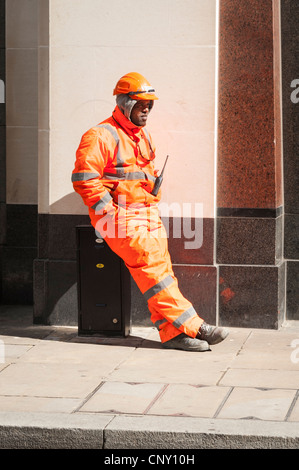 Stadt London ethnischen britische Arbeiter Arbeiter in Tag glow suit Helm sitzt im Frühling Sonne Sonnenbaden auf Metall tfl Abzweigdose Stockfoto