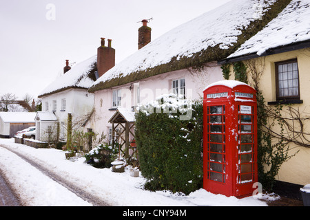 Verschneite Hütten und traditionelle Telefonzelle im Dorf von Morchard Bischof, Devon, England. Stockfoto