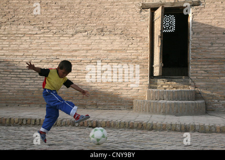 Usbekische Jungen spielen Fußball in Itchan Kala, eine mittelalterliche ummauerte Innenstadt in Chiwa, Usbekistan. Stockfoto