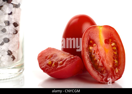 Frische Tomaten mit Salz und Pfeffer Mühle als eine Nahaufnahme vor weißem Hintergrund Stockfoto