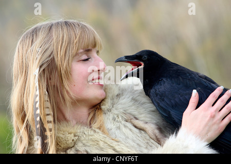 Kolkrabe (Corvus Corax), auf dem Arm einer jungen Frau Stockfoto