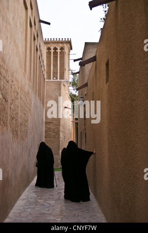 Zwei arabische Frauen in traditioneller Kleidung unter den windtowers in Bastakiya, Dubai, Vereinigte Arabische Emirate Sicht nach hinten. Stockfoto