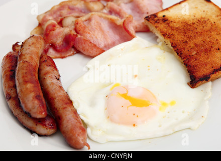 Traditionelle, ungesund, Englisch Frühstück mit gebratenem Speck, Ei, Chipolata Wurst und Brot gekocht Stockfoto