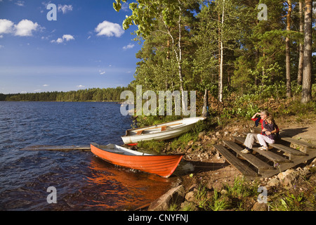 Mutter und Tochter sitzen am Ufer des Sees Algunnen, Schweden, Sm Land, Alsterbro Stockfoto