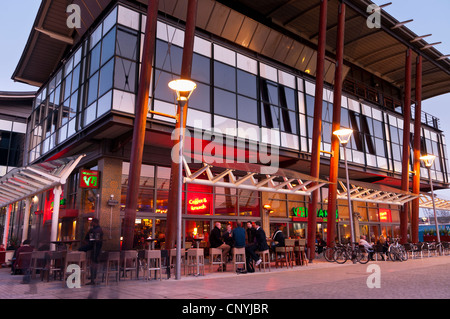 Leute sitzen am Tisch für draußen im Millennium Square in Bristol, Großbritannien Stockfoto