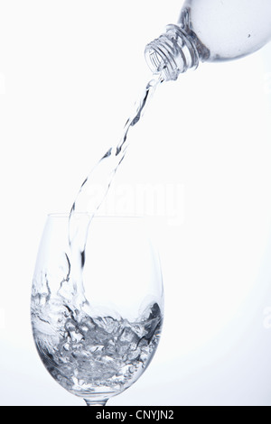 Wasser aus der Flasche in das Glas gießen Stockfoto