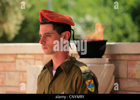 Der israelische Soldat der Kommandoeinheit der Heimatfront steht fest über dem Grab eines gefallenen Soldaten am Yom Hazikaron Memorial Day für die gefallenen Soldaten im jüdischen Begräbnisplatz Kiryat Shaul im Norden von Tel Aviv, Israel Stockfoto