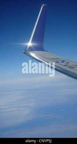 Blick aus dem Fenster eines Flugzeugs fliegen hoch über den Wolken auf einem Leitwerk an einem Flügel Stockfoto