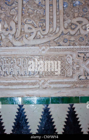 Palast von Alhambra, Granada, Andalusien, Spanien. Detail der kunstvoll geschnitzten Wand und Fliesen. Stockfoto