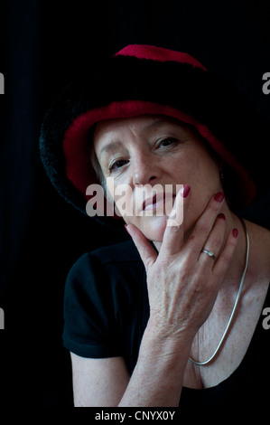 Mittlere gealterte Frau mit roten und schwarzen Hut Stockfoto