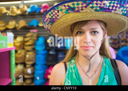 Junge Frau, die versucht, auf einen Sombrero-Hut in einem Hut-Geschäft Stockfoto