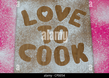 Liebe zu Kochen Eindruck in Puderzucker auf einem Holzbrett Stockfoto