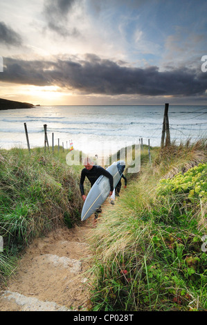 Zwei Surfer verlassen den Strand von Newquay Stockfoto