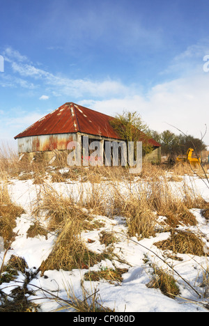 Rostige alte Wirtschaftsgebäude Landmaschinen im Winter mit Schnee auf dem Boden gespeichert Stockfoto