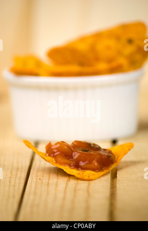 würzige Tortilla-Chips und Tomaten-Salsa-Dip über Holzbrett Stockfoto