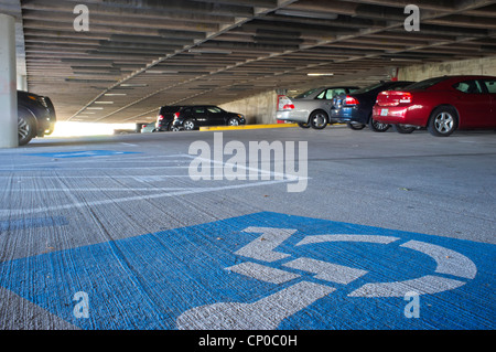 Behinderten Parkplatz markiert mit Rollstuhl auf blauem Hintergrund in einem öffentlichen Parkhaus Stockfoto
