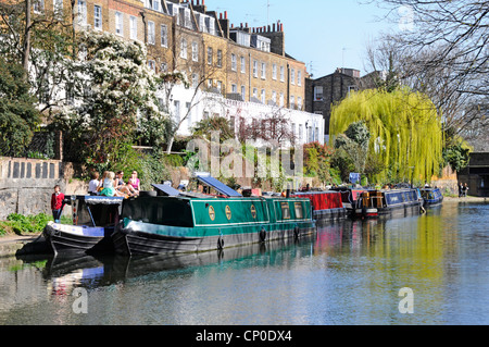 Regents Canal sonnige Schmalbootverankerungen & Immobilien Menschen, die auf dem Weg zum Schleppweg spazieren, Frühlingsfarbe auf dem Weeping Willow Tree Islington London England Großbritannien Stockfoto
