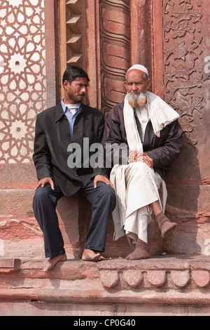 Fatehpur Sikri, Indien. Zwei Männer reden außen Eingang, Jama Masjid (Moschee Dargah).  Westliche und traditionelle Kleidung. Stockfoto