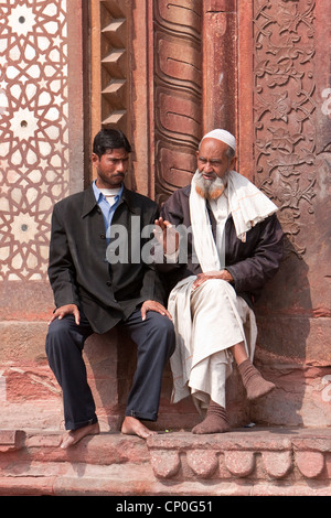 Fatehpur Sikri, Indien. Zwei Männer reden außen Eingang, Jama Masjid (Moschee Dargah).  Westliche und traditionelle Kleidung. Stockfoto