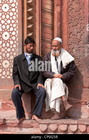 Fatehpur Sikri, Indien. Zwei Männer reden außen Eingang, Jama Masjid (Moschee Dargah).  Westliche und traditionelle Kleidung. Stockfoto