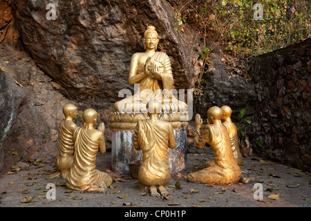 Sitzen mit gekreuzten Beinen Buddha und Mönche beten auf dem Weg zum Mount Phu Si Gipfel, der das Zentrum der alten Luang Prabang dominiert. Stockfoto