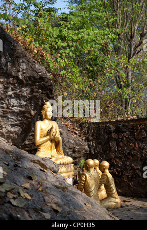 Sitzen mit gekreuzten Beinen Buddha und Mönche beten auf dem Weg zum Mount Phu Si Gipfel, der das Zentrum der alten Luang Prabang dominiert. Stockfoto