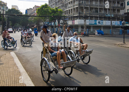 Horizontale Ansicht des Zyklus Rikschas, die westliche Touristen Tragen von Gesichtsmasken auf die Straßen von Ho Chi Minh City, Vietnam. Stockfoto
